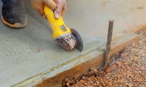 Obrero de la construcción está cortando concreto. 