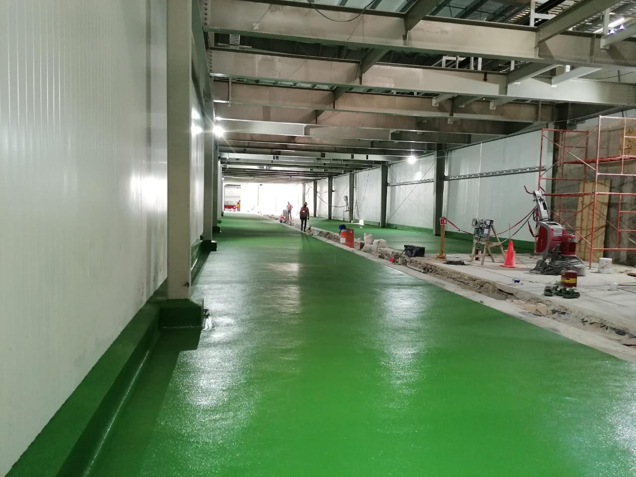 Construcción de piso de uretano en color verde con maquinaria especializada.
